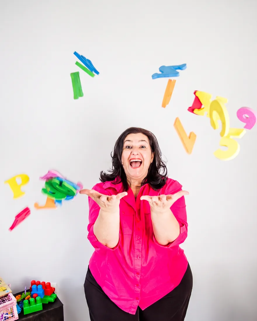 Sandra Andreotti sorrindo com letras e números coloridos no ar