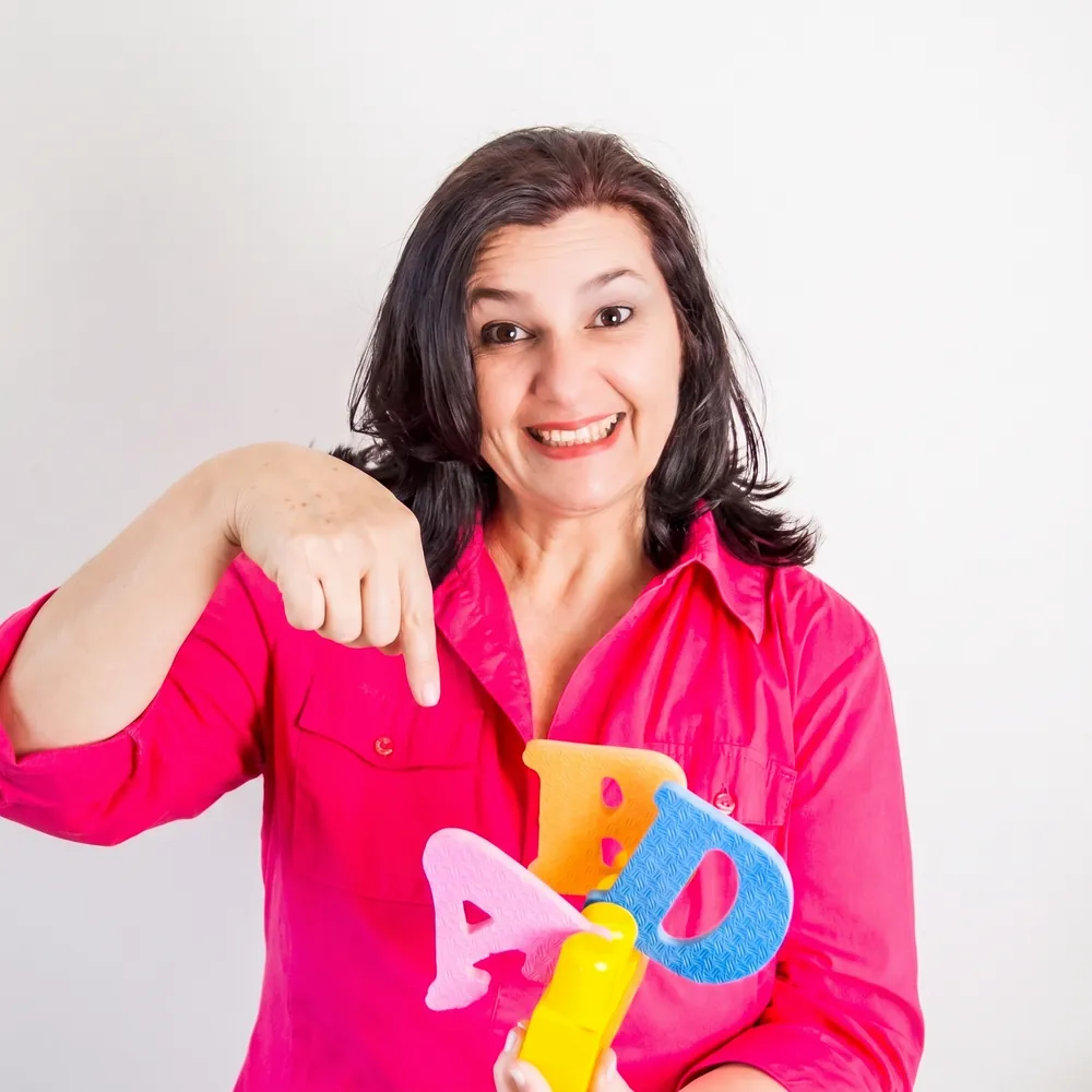 Sandra Andreotti, psicopedagoga e alfabetizadora, segurando letras coloridas